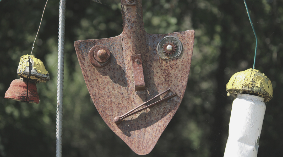 artwork face made from screws and clips on rusty metal trowel